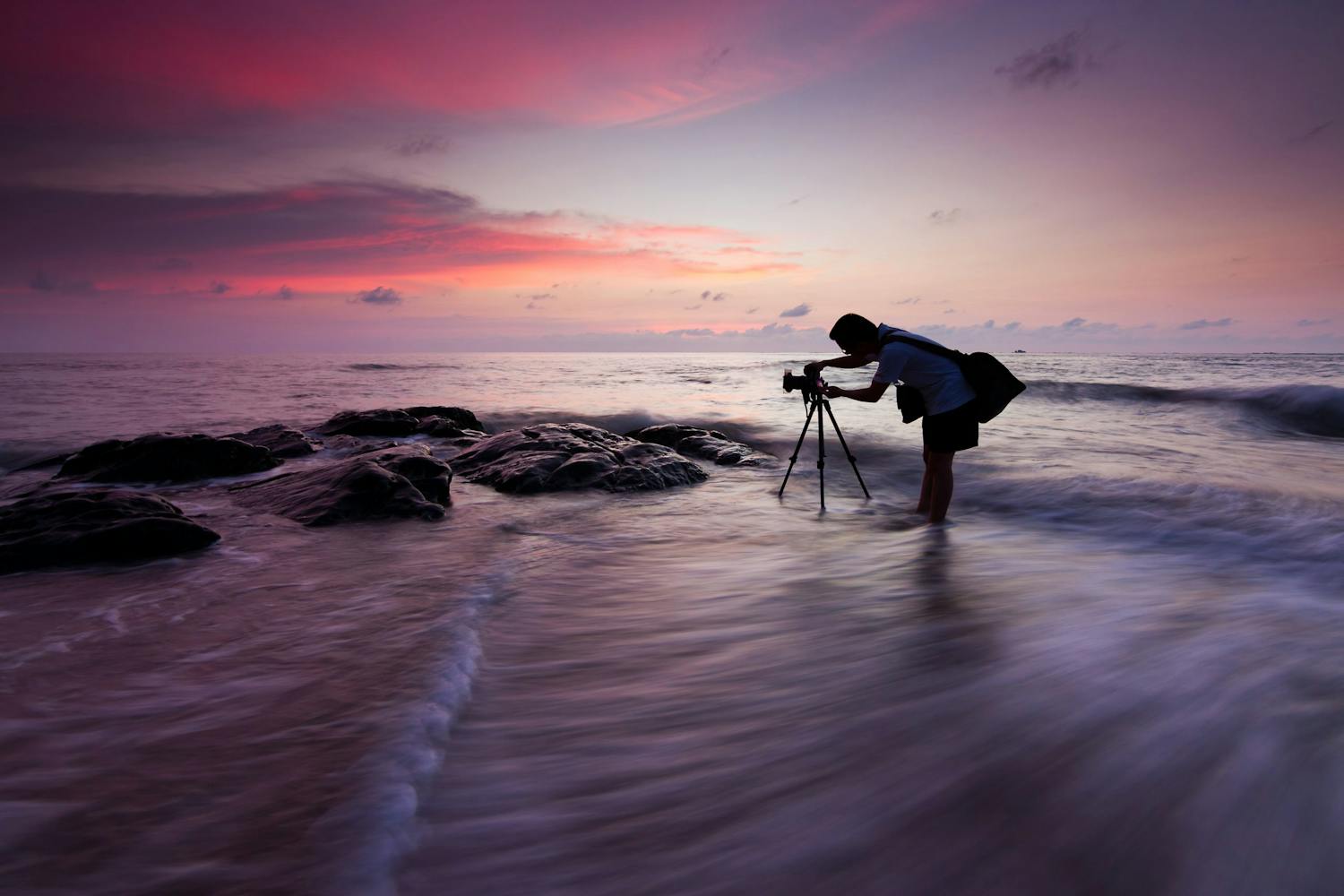 Man fotograferar solnedgången vid stranden.
